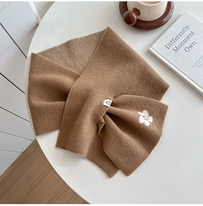 Close-up of brown knit scarf with white flower detail and soft cashmere texture