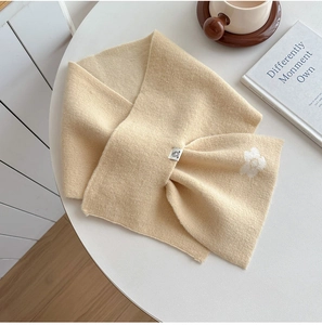 Detail shot of a soft cream knitted scarf with delicate white floral patterns