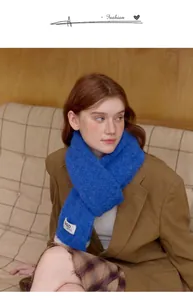 Close-up of royal blue knitted scarf with soft wool texture and GQD patch detail