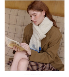 Detail of soft off-white knitted wool scarf with contrast blue edge and GQD label