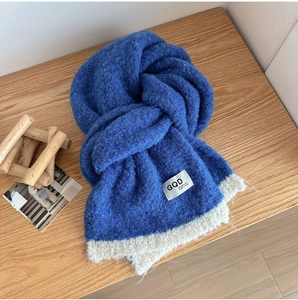 Close-up of electric blue knitted wool scarf with soft fluffy texture and white tag