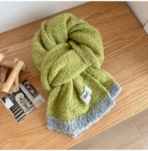 Detail of chunky knit wool scarf in grass green and grey with GQ brand label