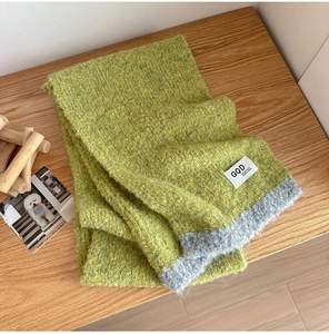 Detail of soft green and grey knit scarf showing fluffy texture and stitched label