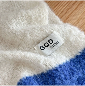 Detail of soft knit wool scarf with blue and white color-blocking and brand label