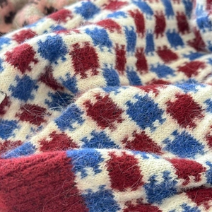 Vue macro d'une écharpe en maille à carreaux rouge et bleu avec texture en laine mohair