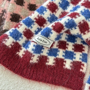 Détail d'une écharpe en maille à carreaux rouge et bleu avec texture douce et étiquette