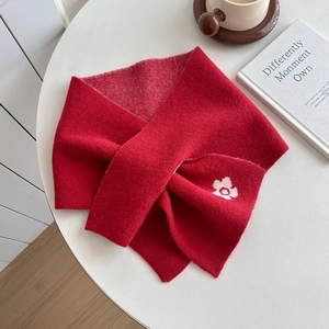 Elegant red knitted winter scarf with white flower detail shown on a cafe table setting