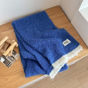 Royal blue knitted scarf with soft wool texture and white contrast trim on wood table
