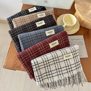 Detail of plaid scarves showing textured knit fabric, fringe edges, and brand labels