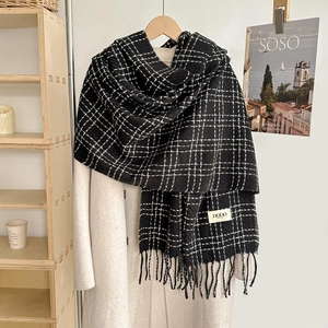 Classic black and white plaid scarf with long fringe on a white wool coat