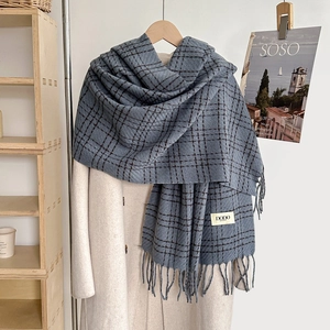 Thick navy blue plaid cashmere-like scarf with fringe and brand label on beige coat