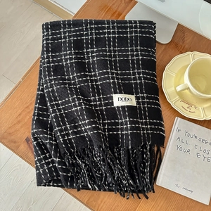 Close-up of black and white checkered scarf with fringe tassels on a wooden table