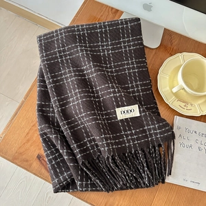 Detail of dark coffee plaid scarf featuring thick tassels and a woven white brand label