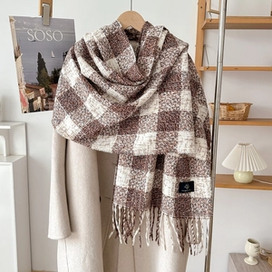 Thick brown and beige checkered cashmere scarf with long tassels over a beige coat