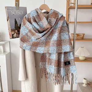 Detail of blue and brown plaid cashmere scarf with tassels styled on a wool coat
