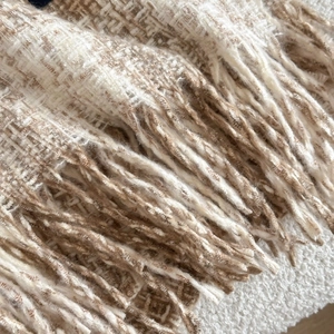 Close-up of beige and brown plaid cashmere scarf texture with elegant fringe detail