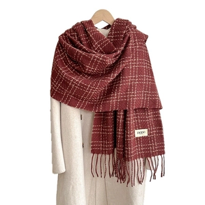 Thick burgundy plaid scarf with tassels styled on white wool coat for winter outfit
