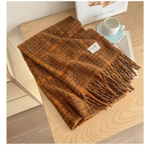 Detail of vintage plaid scarf with long tassels and white woven label on wooden surface