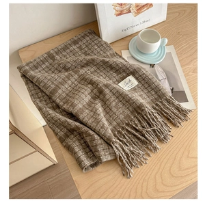 Close-up of brown plaid scarf with soft fringe edges and a minimalist fabric label