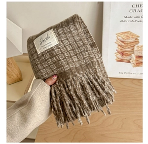 Close-up of dark brown plaid knit scarf texture with fringe and brand label