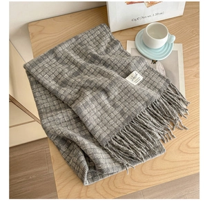 Detailed macro of grey and white checkered scarf with soft fringe on wooden surface