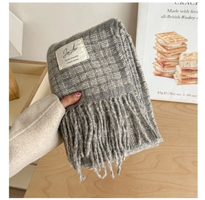Detailed texture of gray checkered knit scarf with soft tassels and white woven label