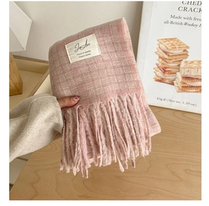 Close-up of pink plaid scarf texture with thick tassels and classic white woven label