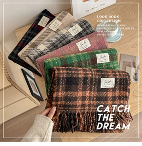 Detail of plaid knit scarves with tassels and labels stacked on a wooden table