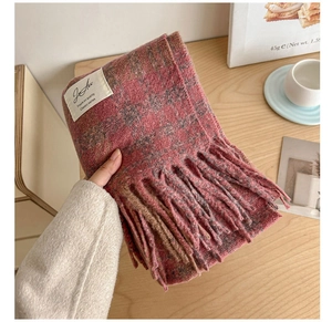 Close-up of pink plaid scarf texture with long fringe and decorative woven label