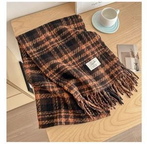 Close-up of classic striped plaid scarf with fringe and white woven label on the surface