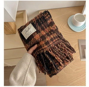 Detail of soft plaid scarf with tassels and classic series label on a wooden desk