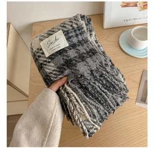 Detail of soft plaid scarf with tassels, featuring thick fabric and woven brand label