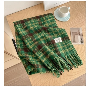 Close-up of green and brown plaid scarf with long fringe and white woven label