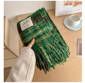 Detailed view of the green-brown checkered knit scarf with fringe and a woven label