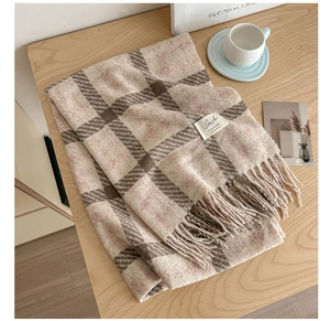 Detail showing soft plaid scarf texture with fringes and beige coffee cup background