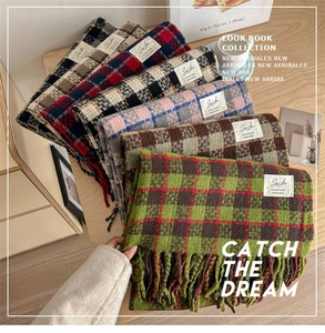 Close-up of assorted colorful plaid tassel scarves neatly stacked on a wooden table
