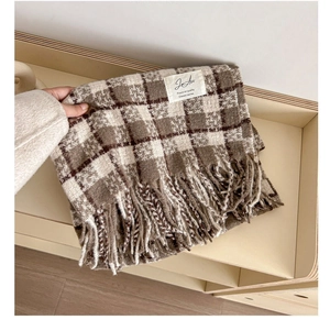 Detail of plaid cashmere-like scarf showing soft texture, fringe, and classic woven label
