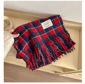 Close-up of soft plaid scarf fabric with red and navy patterns and fringe details