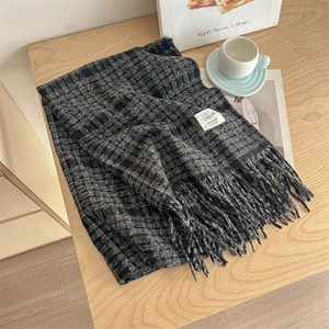 Classic black and white plaid scarf with fringe on a wooden table with lifestyle props