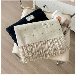 Detail of knit scarves with colorful polka dots, long fringe, and decorative woven labels