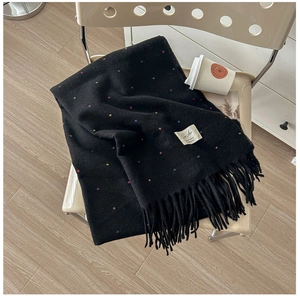 Detail of soft black knit scarf with colorful specks and thick fringe on a chair