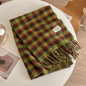 Soft checkered cashmere-like scarf in green and brown with tassels on a white table