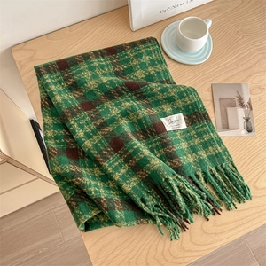 Soft striped checkered scarf with tassels in green and yellow on a wooden table