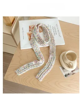 Close-up of rainbow speckled knit scarf with a textured ribbed pattern and brand label