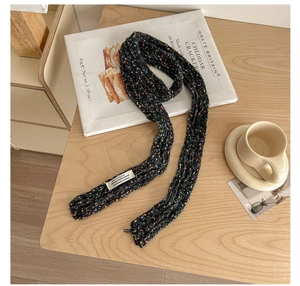 Close-up of black chunky knit scarf with rainbow speckled yarn and woven brand label