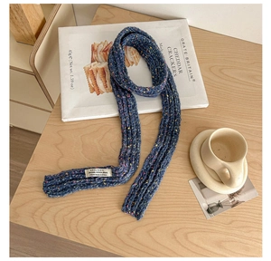 Close-up of navy knit scarf with colorful dots and a white brand label on wood
