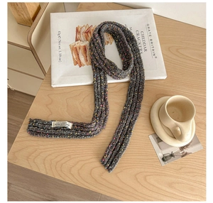 Close-up of dark grey confetti knit scarf with brand label on wooden table setting