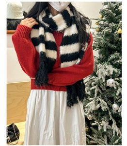 Detail of black and white striped knit scarf with decorative tassels in a festive setting