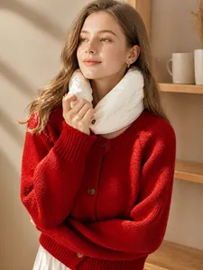 Close-up of bright red chunky knit cardigan with buttons and white puffed down neck warmer