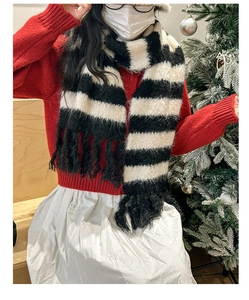 Detail of soft knit scarf with black and white stripes and tassel ends in festive setting